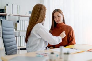 Female medical provider giving a consultation to another female woman in an orange shirt